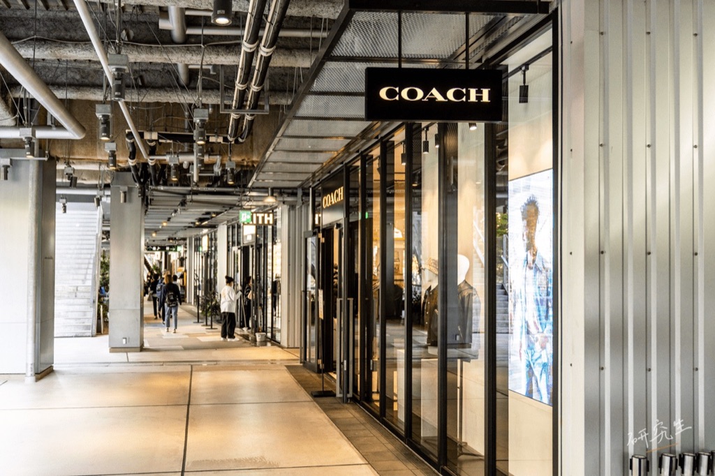 一整排路面店的走廊，看得到 COACH 與 KITH 的招牌